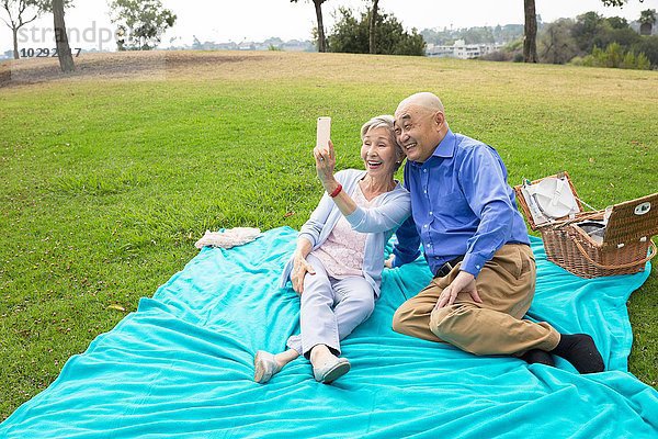 Seniorenpaar beim Picknick im Park  Selbstporträt mit dem Smartphone