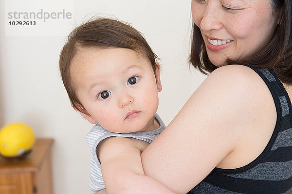 Porträt des süßen Jungen in den Armen reifer Mütter