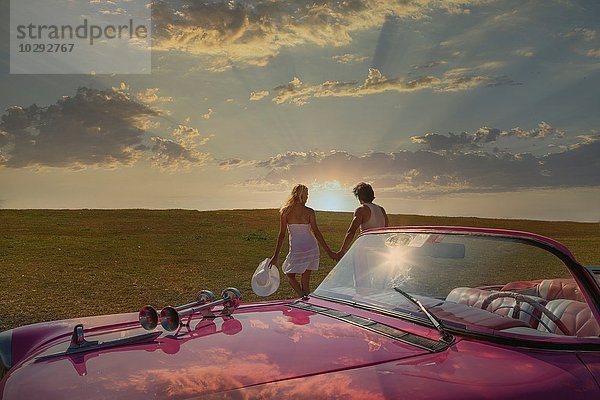 Paar mit ihrem Cabrio auf dem Feld