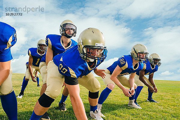 Team von jugendlichen und erwachsenen American Football-Spielern  die sich auf dem Übungsgelände versammeln.