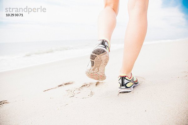 Mittlere erwachsene Frau beim Gehen am Strand  Rückansicht  niedriger Abschnitt