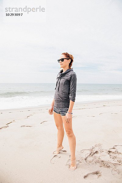 Mittlere erwachsene Frau am Strand stehend  mit Blick auf die Aussicht