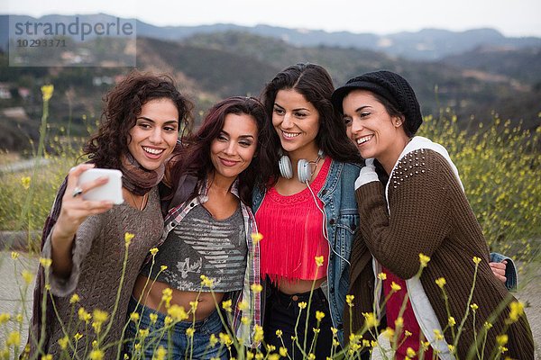 Vier erwachsene Schwestern posieren für Smartphone Selfie auf der Landstraße