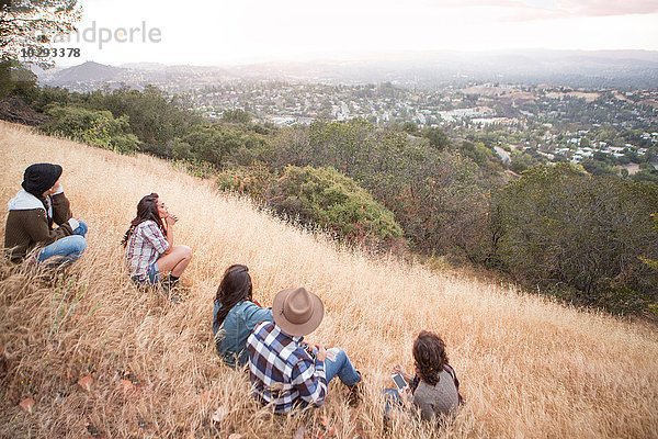 Junger Mann und vier erwachsene Schwestern  die vom grasbewachsenen Hügel hinausblicken.