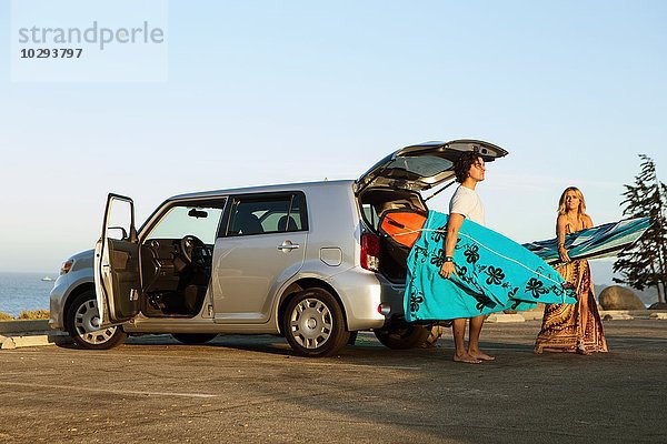 Paar  das Surfbretter aus dem Kofferraum des Autos nimmt