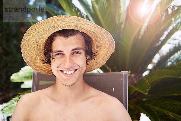 Porträt eines lächelnden jungen Mannes mit Sonnenhut