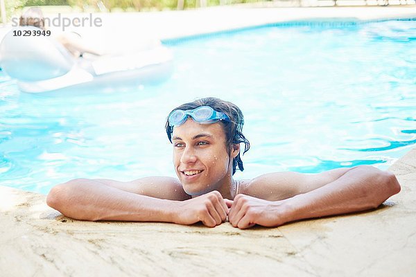 Porträt eines lächelnden jungen Mannes mit nassen Haaren im Schwimmbad