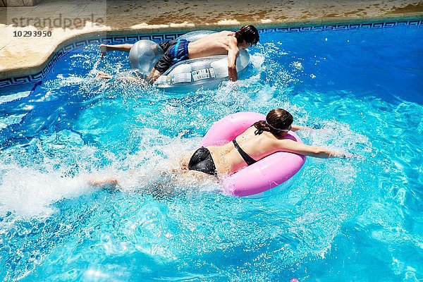 Junger Mann und jugendliche Schwester auf Hüpfburgen im Schwimmbad