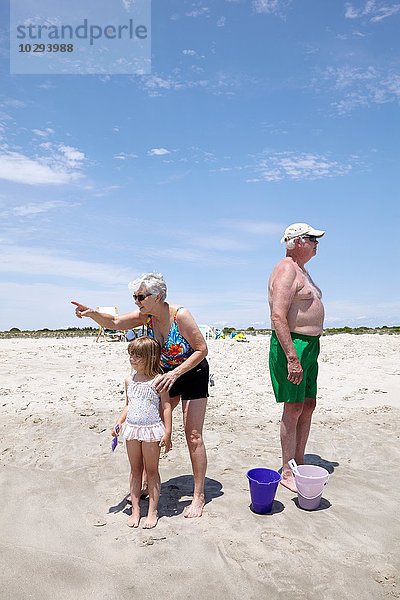 Seniorin mit Enkelin  die auf den Strand zeigt und schaut.