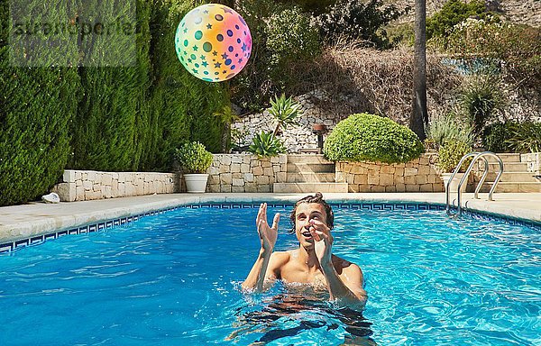 Junger Mann wirft Ball ins Schwimmbad