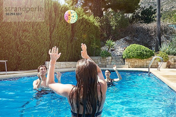 Teenager Mädchen wirft Ball zu Mutter und Bruder im Schwimmbad