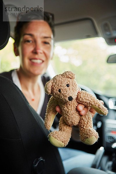 Frau im Auto sitzend  Teddybär durch die Sitze gehend