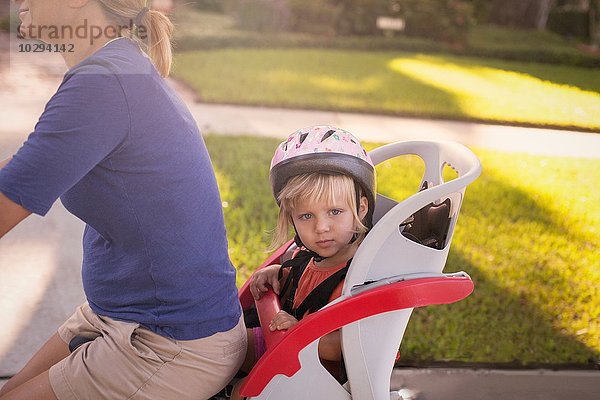 Reife Frau auf dem Fahrrad mit Tochter auf dem Kindersitz hinter ihr