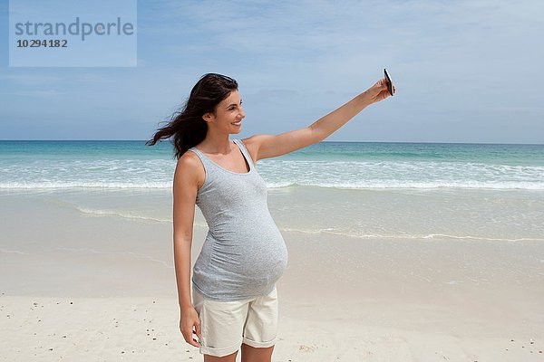 Schwangere mittlere erwachsene Frau nimmt Selfie auf Smartphone am Strand  Kap Verde  Afrika