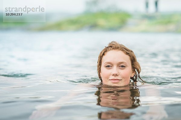 Porträt einer ruhigen jungen Frau  die in der Geheimen Lagune schwimmt (Gamla Laugin)  Fludir  Island