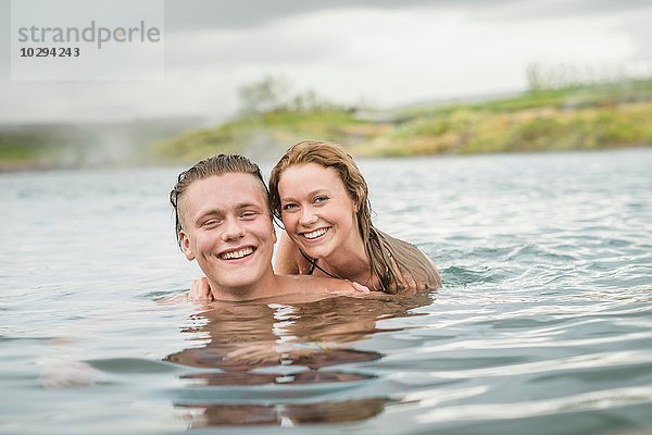Porträt eines lächelnden jungen Paares  das sich in der Secret Lagoon Thermalquelle (Gamla Laugin)  Fludir  Island  entspannt.