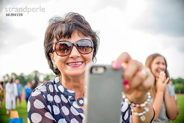 Reife Frau beim Fotografieren mit dem Smartphone