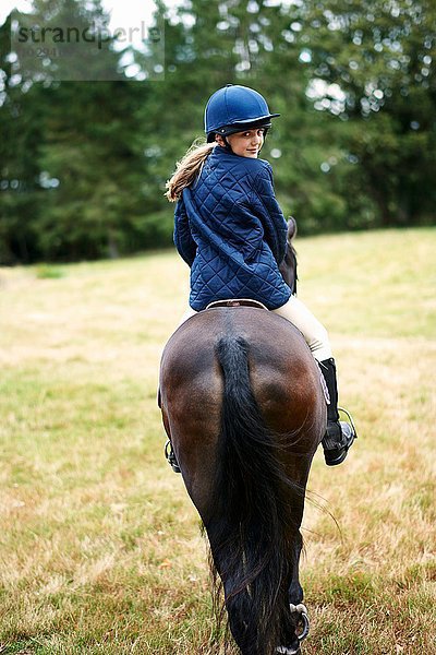 Rückansicht des Mädchens beim Reiten auf dem Feld