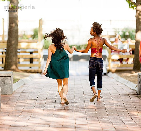 Junge Frauen  die auf der Kopfsteinpflasterstraße laufen.