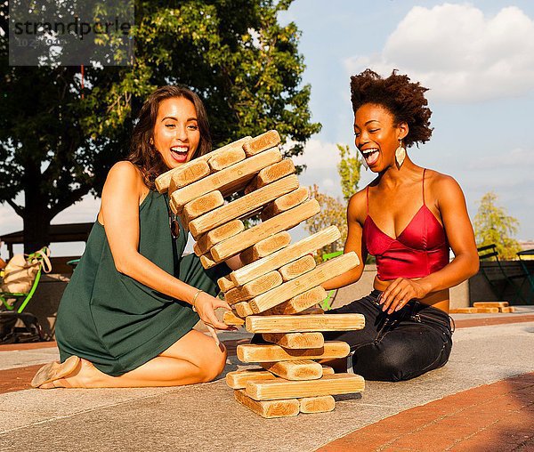Junge Frauen spielen mit Bausteinen auf dem Boden