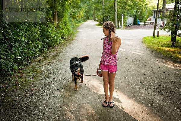 Vorderansicht des Mädchens auf Schotterpiste  gehender Hund  Blick über die Schulter
