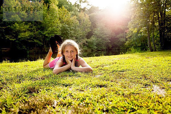 Oberflächliche Ansicht des auf Gras liegenden Mädchens mit Blick auf die Kamera