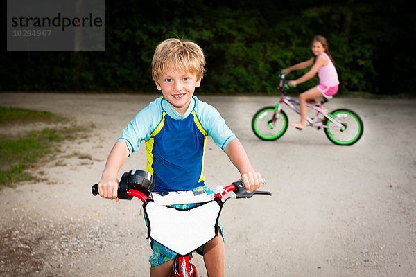 Junge und Mädchen auf Fahrrädern mit lächelndem Blick auf die Kamera