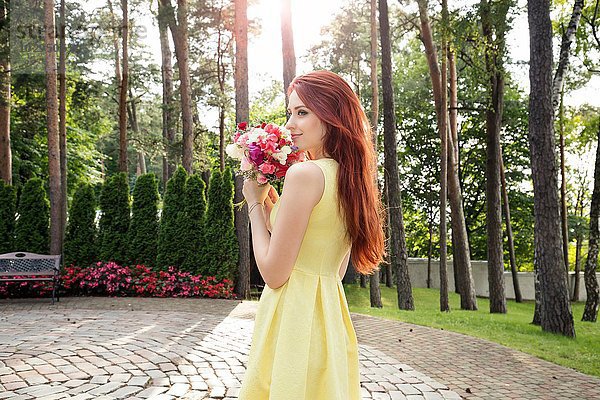 Junge Frau mit Blumenstrauß im Park