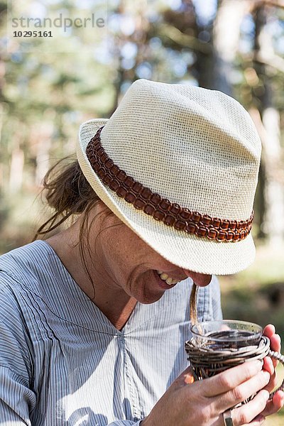 Reife Frau lacht beim Teetrinken im Wald