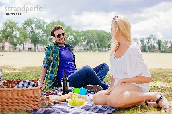 Paar sitzt auf einer Decke und macht ein Picknick.