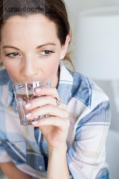 Abgeschnittene Ansicht einer reifen Frau  die ein Glas Wasser trinkt.