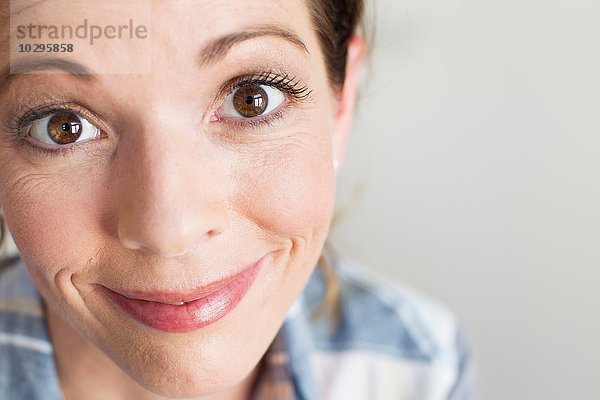 Ausschnitt einer reifen Frau mit braunem Auge  die lächelnd in die Kamera schaut.