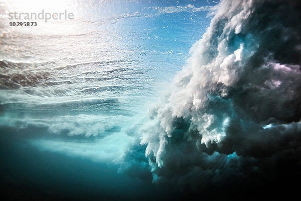 Unterwasseransicht einer riesigen Welle  die über ein flaches Riff stürzt.