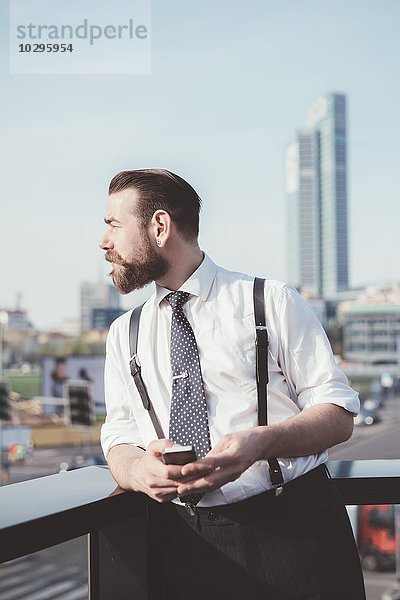 Stilvoller Geschäftsmann mit Blick vom Bürobalkon aus