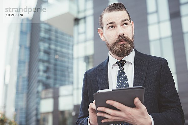 Stilvoller Geschäftsmann mit digitalem Tablett-Touchscreen außerhalb des Büros