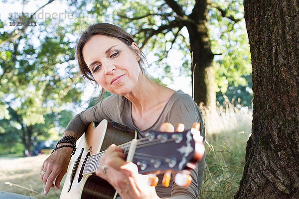 Reife Frau spielt Akustikgitarre im Park