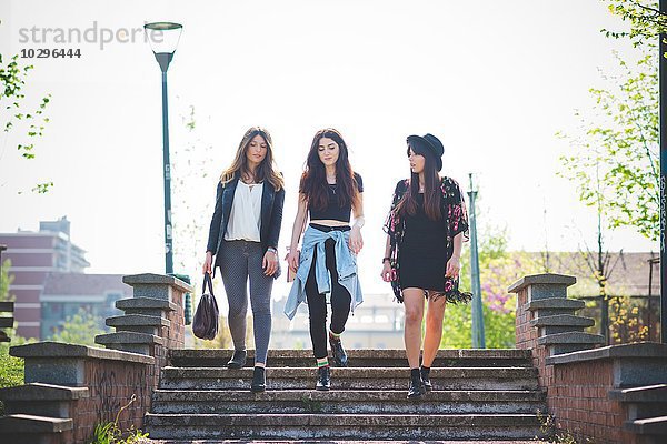 Drei junge Freundinnen schlendern die Parktreppe hinunter.