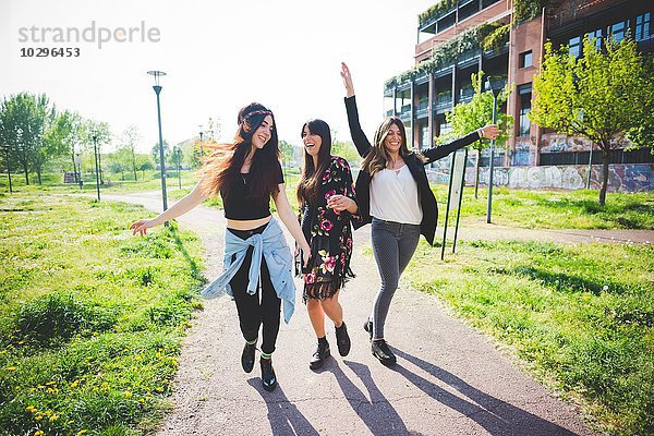 Drei junge Freundinnen tanzen zusammen im Park.