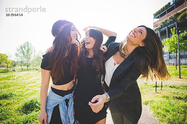 Drei junge Freundinnen  die zusammen im Park lachen.