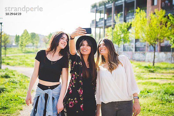 Drei junge Freundinnen posieren für Smartphone Selfie im Park