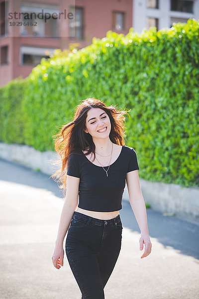 Schöne junge Frau mit langen braunen Haaren beim Spazierengehen