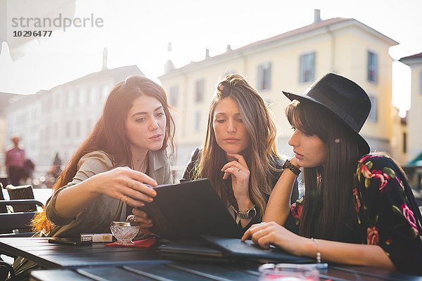 Drei junge Frauen lesen Update auf digitalen Tablette im Bürgersteig Cafe