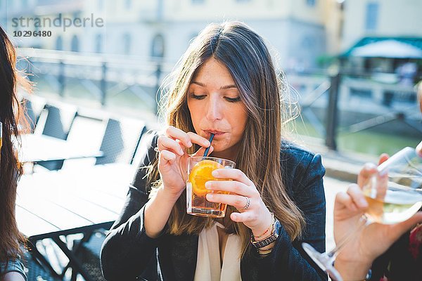 Junge Frau und Freunde trinken Cocktails am Waterfront Café