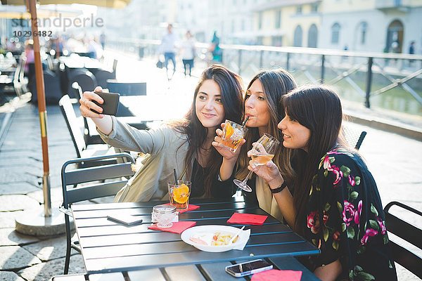 Drei junge Frauen posieren für Smartphone Selfie am Waterfront Café