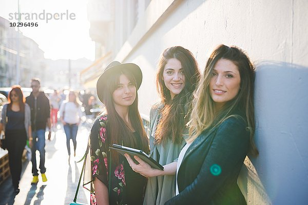 Porträt von drei jungen Frauen mit digitalem Tablett auf der Stadtstraße
