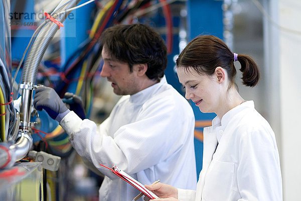 Seitenansicht der männlichen und weiblichen Kollegen im Laborkittel  mit Zwischenablage