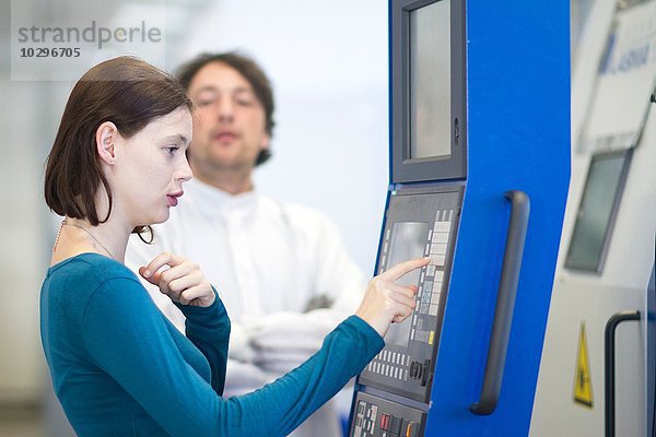 Seitenansicht der jungen Frau beim Drücken der Tastatur an wissenschaftlichen Geräten