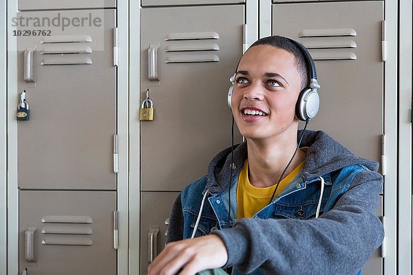 Student lehnt sich an Schließfächer  Musik hören mit Kopfhörern