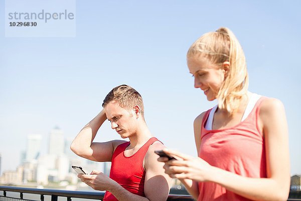 Läufer mit Smartphone auf der Brücke
