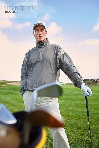 Golfer mit Golfschläger  Hand in Tasche  Blick in die Kamera
